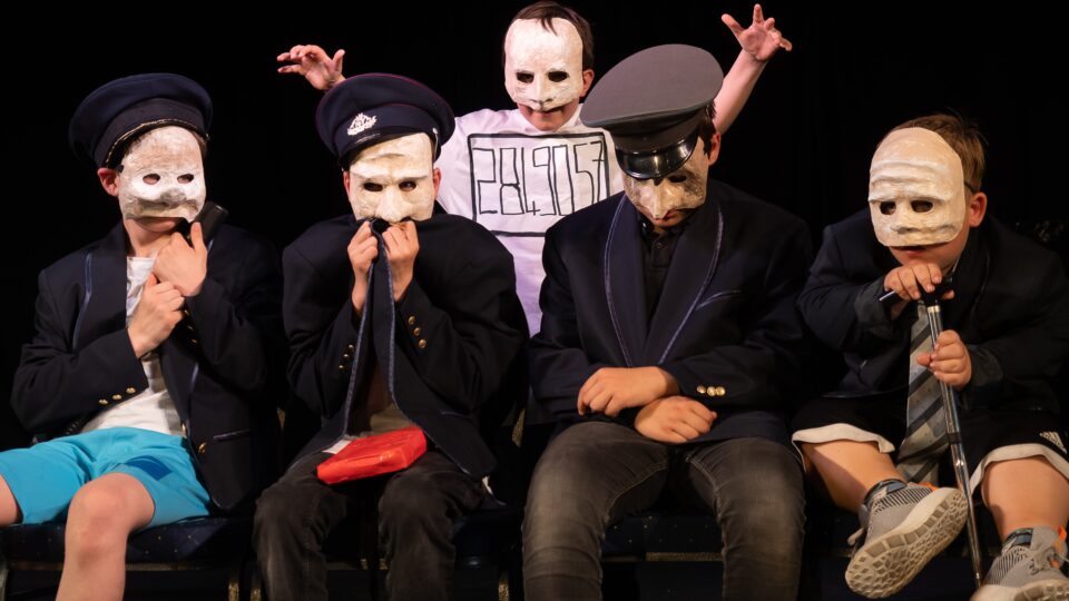 Fünf Personen mit und ohne Behinderung posieren gemeinsam mit weißen Masken im Gesicht in die Kamera
